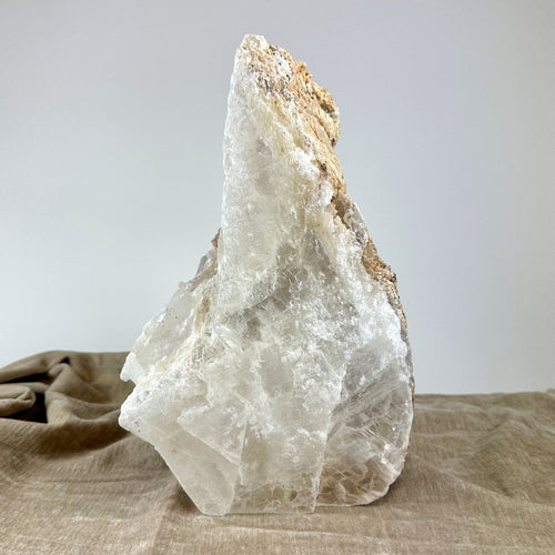 Mexicansk Selenit lampe nr 19 på en lys beige klud, en stor, ujævn krystal med naturlige mineraltoner.