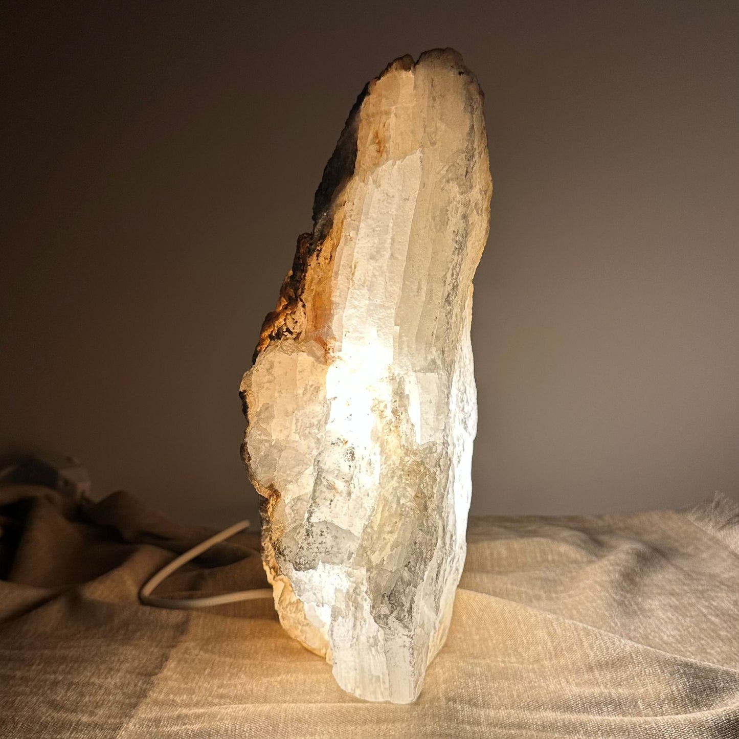 Mexicansk Selenit lampe nr 19 på en bordplade, skaber en varm og beroligende belysning i et dæmpet rum.