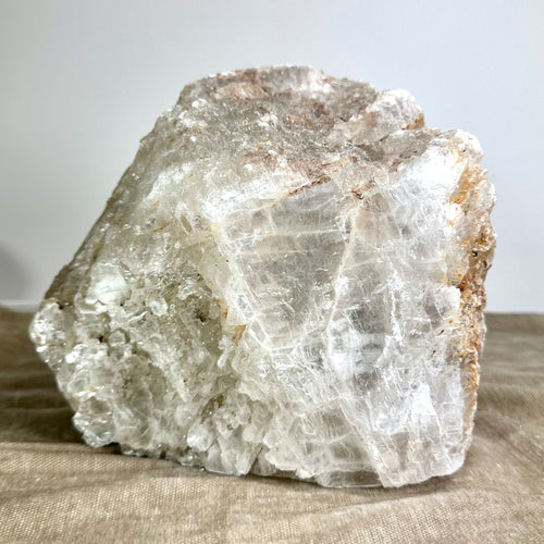 Mexicansk Selenit lampe nr 56, naturlig hvid krystal med glat og rug tekstur på en beige overflade.