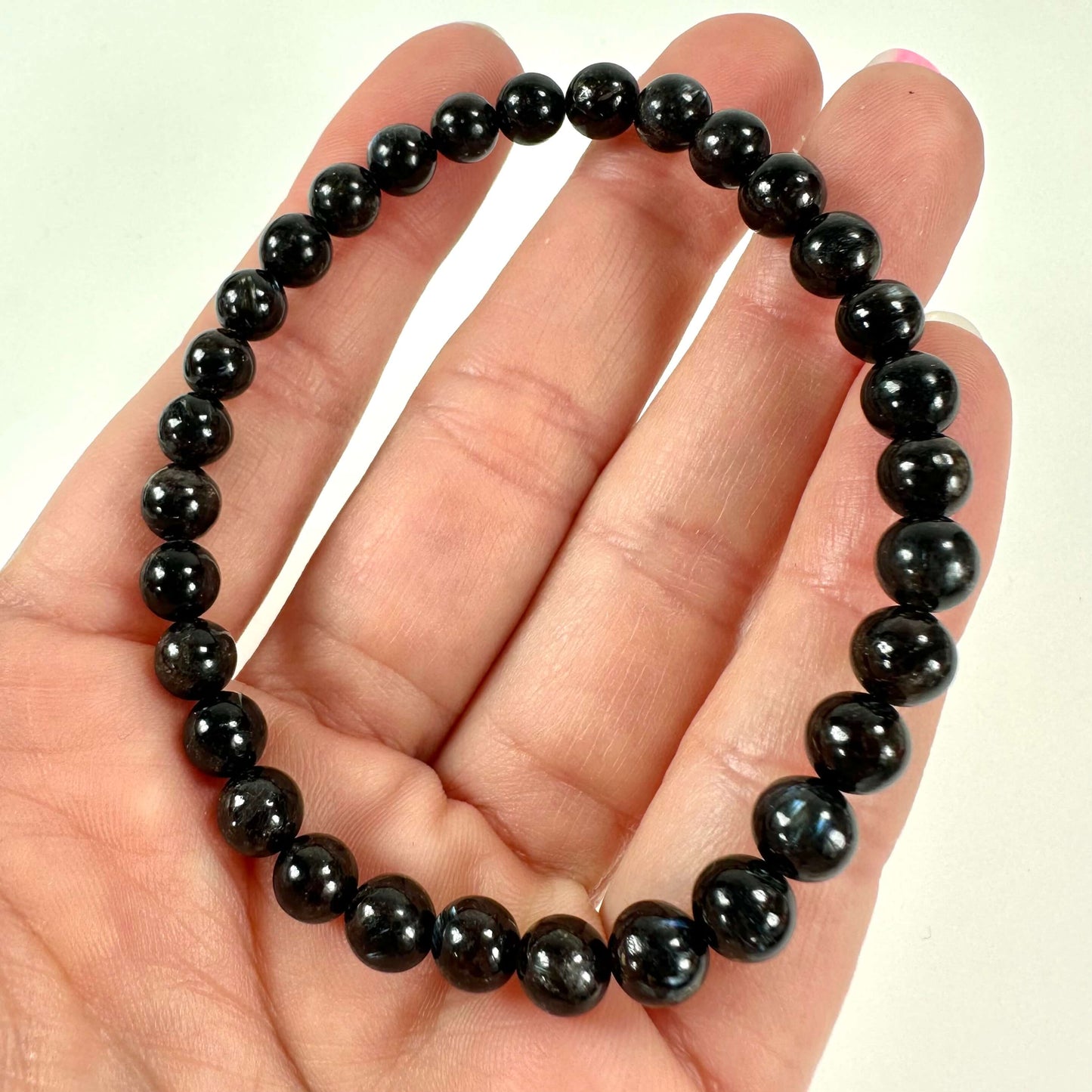 Astrophylit armbånd med sorte perler holdes i en hånd.