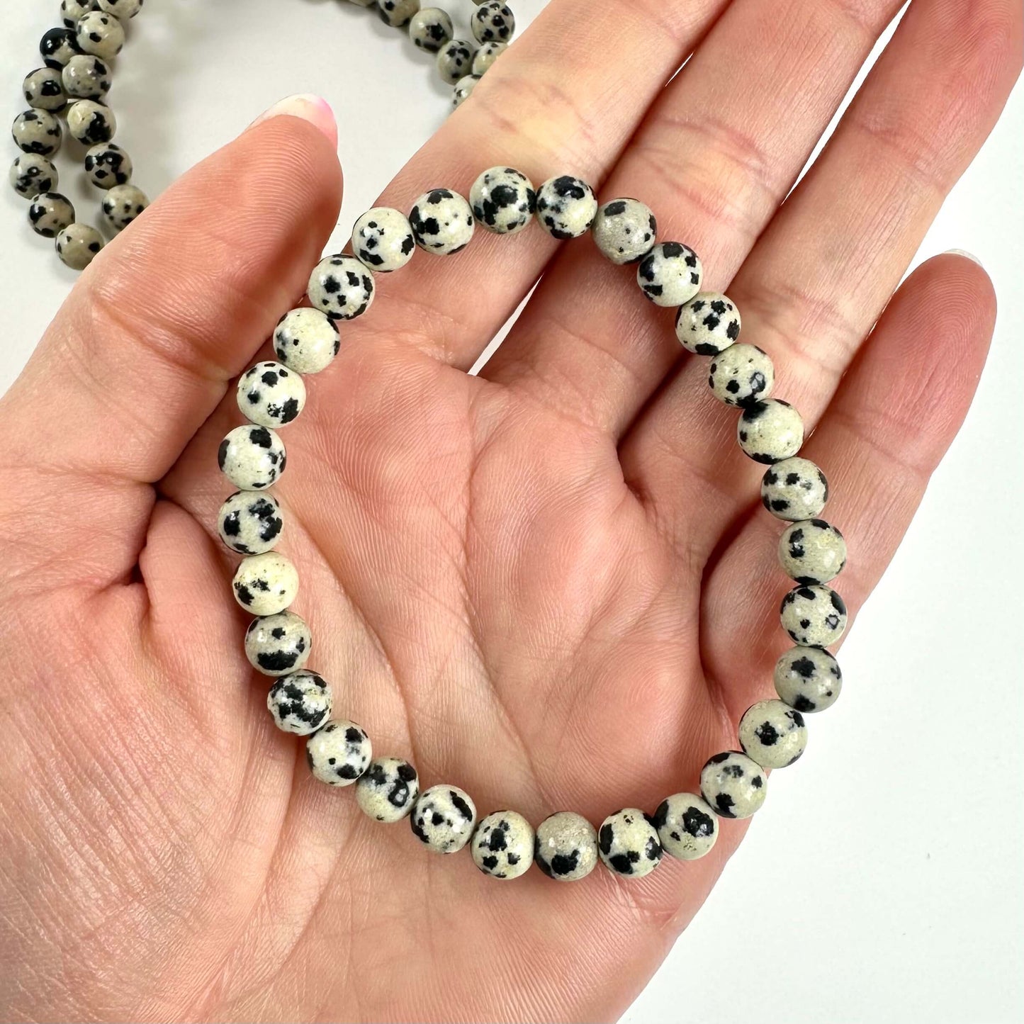 En hånd holder et dalmatiner armbånd lavet af perler med sorte og hvide pletter.