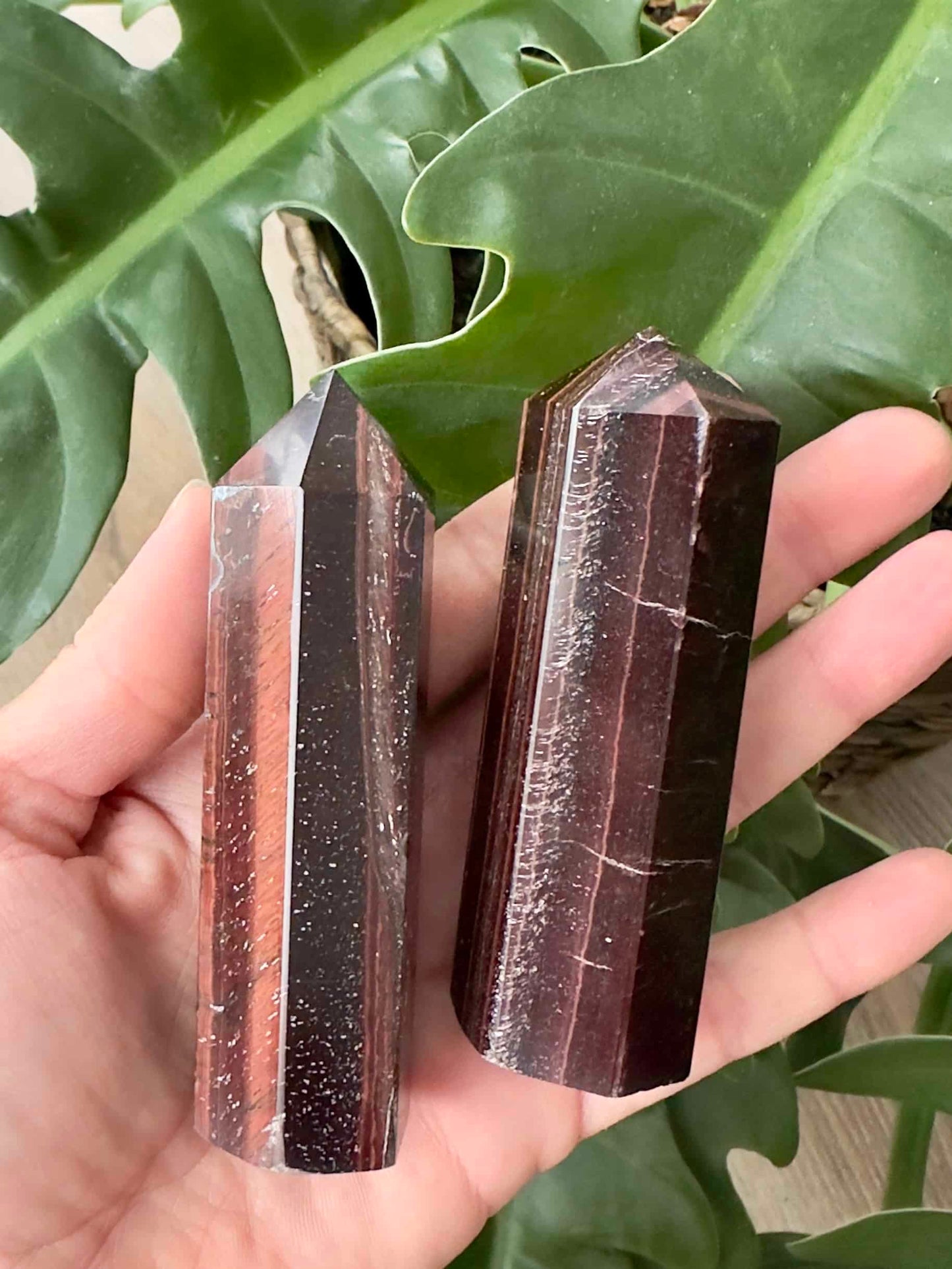 To Okseøje tårne, holdt i en hånd, med grønne blade i baggrunden.