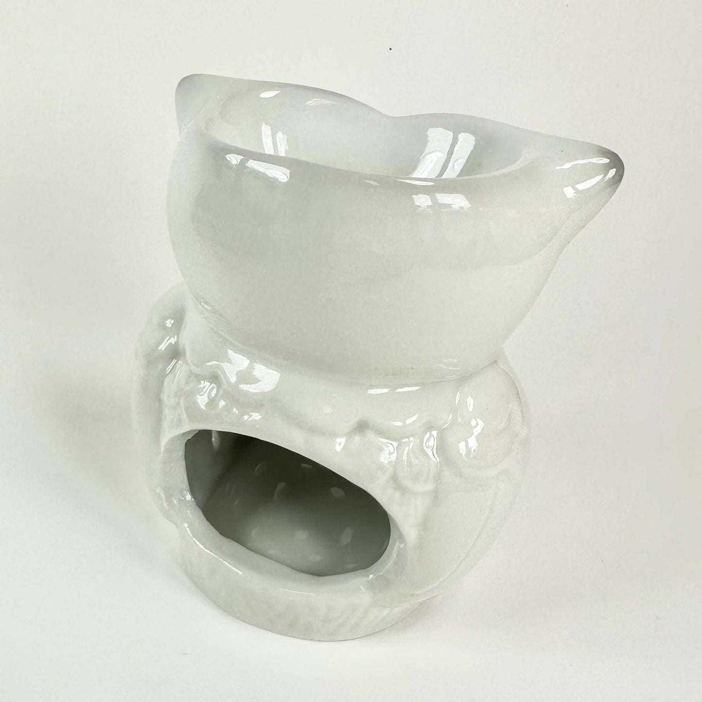 Hvid keramisk oliebrænder med katteformet top og hul til fyrfadslys.