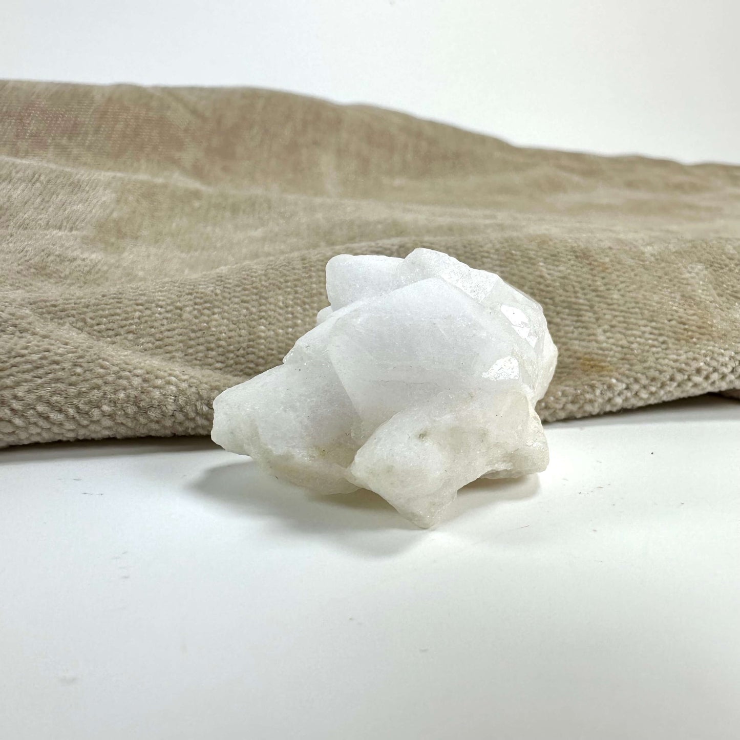 Blomster kvarts klynge placeret på en blød, beige overflade i et lyst miljø.