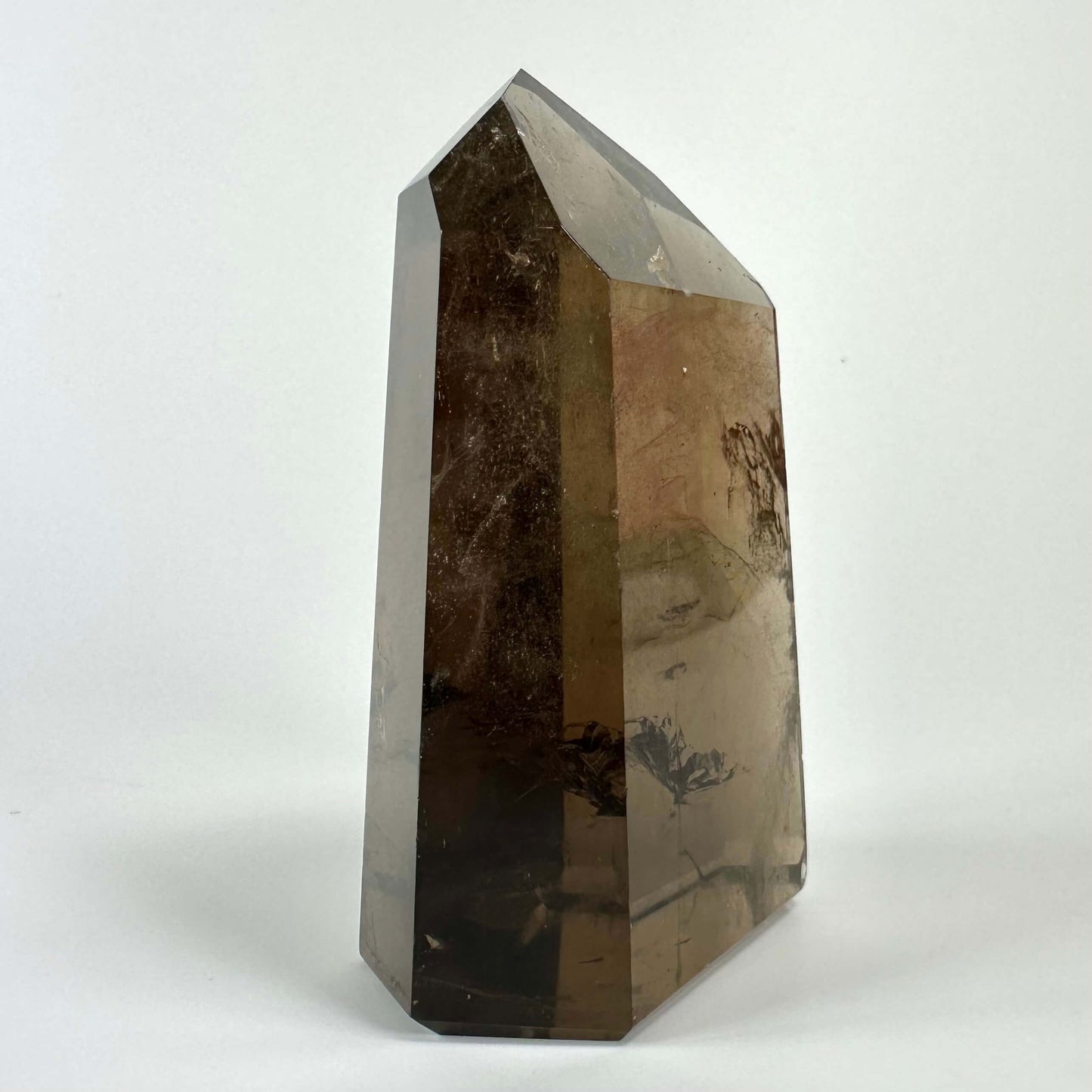 Røgkvarts tårn med en glat, poleret overflade og brune nuancer på en hvid baggrund.