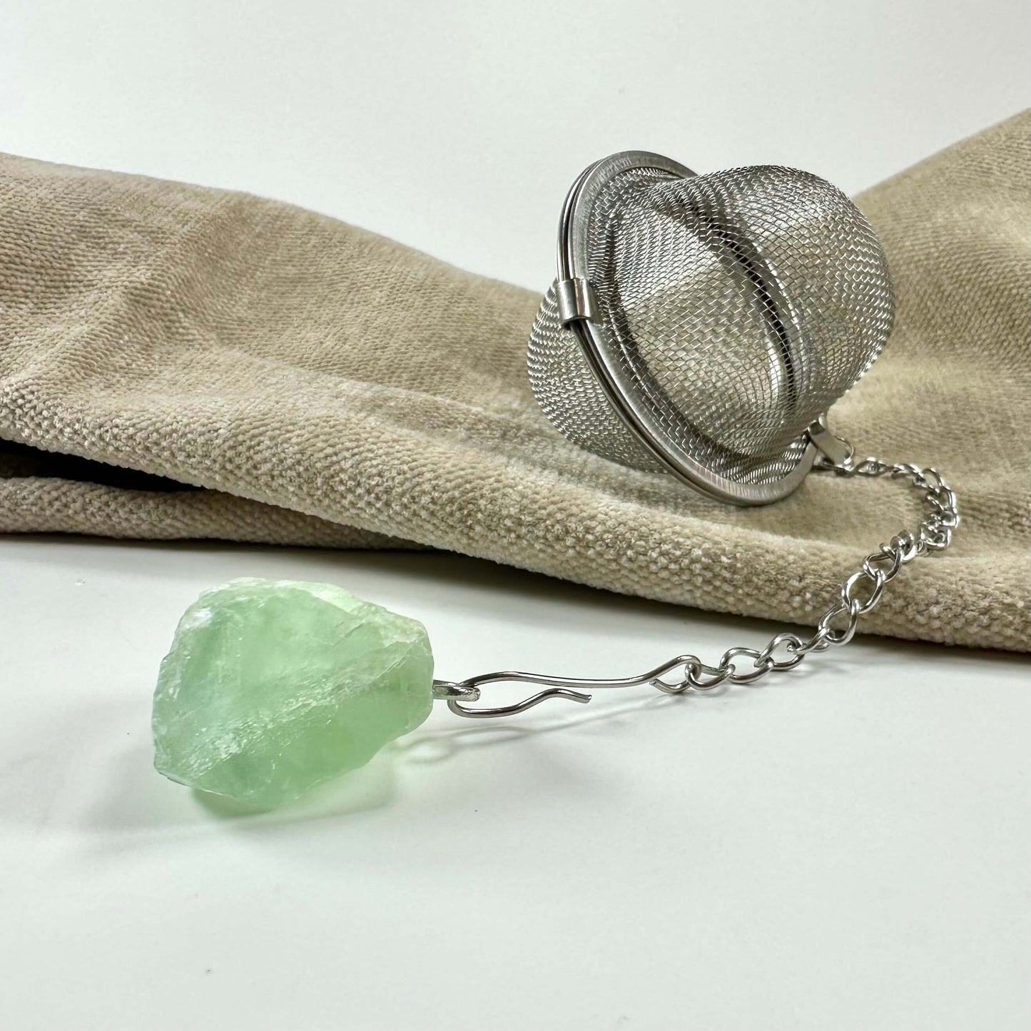 Tesi uden indhold og en grøn krystal på en stofoverflade.