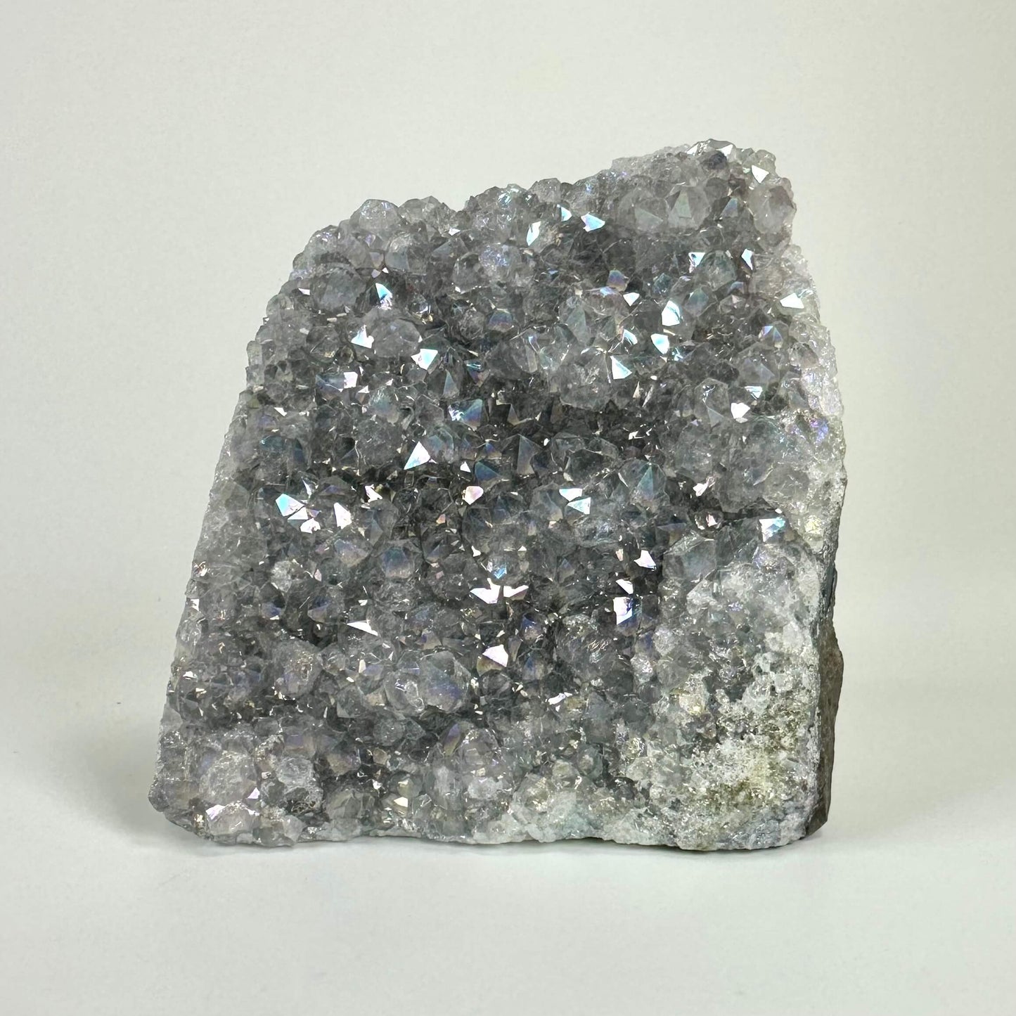 Ametyst aura geode med glitrende krystaller på en lys baggrund.