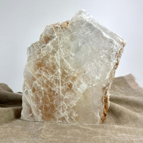 En stor, naturlig selenit krystal oplyst på en stofbaggrund.