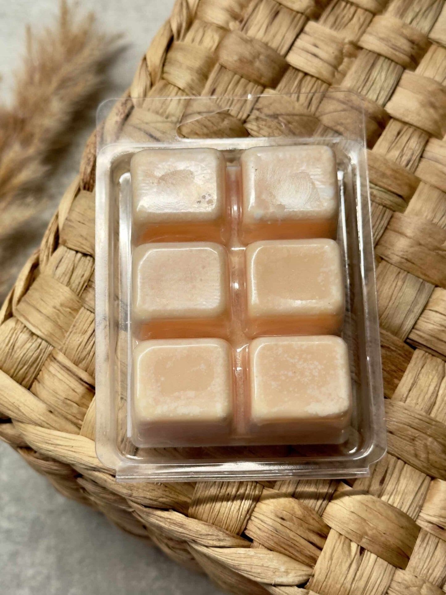 En bakke med seks terninger af soyavoks i papayaduft på en flettet kurv.