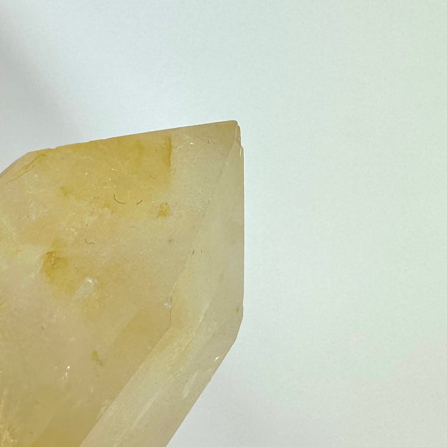 Golden healer obelisk mod en hvid baggrund, der fremhæver dens varme gyldne nuancer og polerede overflade.