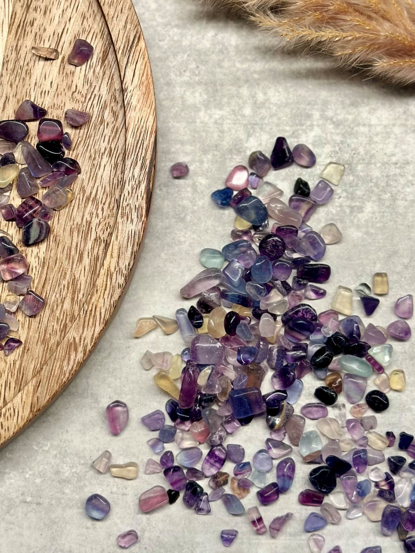 Fluorit mini-sten i forskellige farver på en træplade og grå overflade.