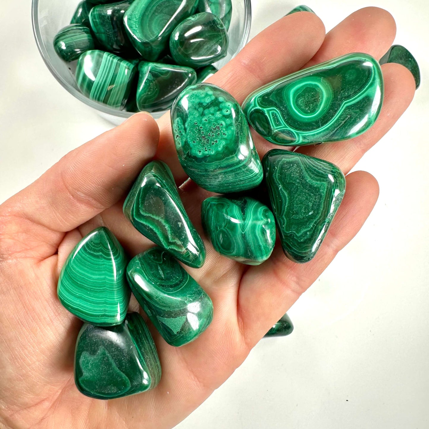 Håndfuld glatte grønne Malakit lommesten med dekorative mønstre.