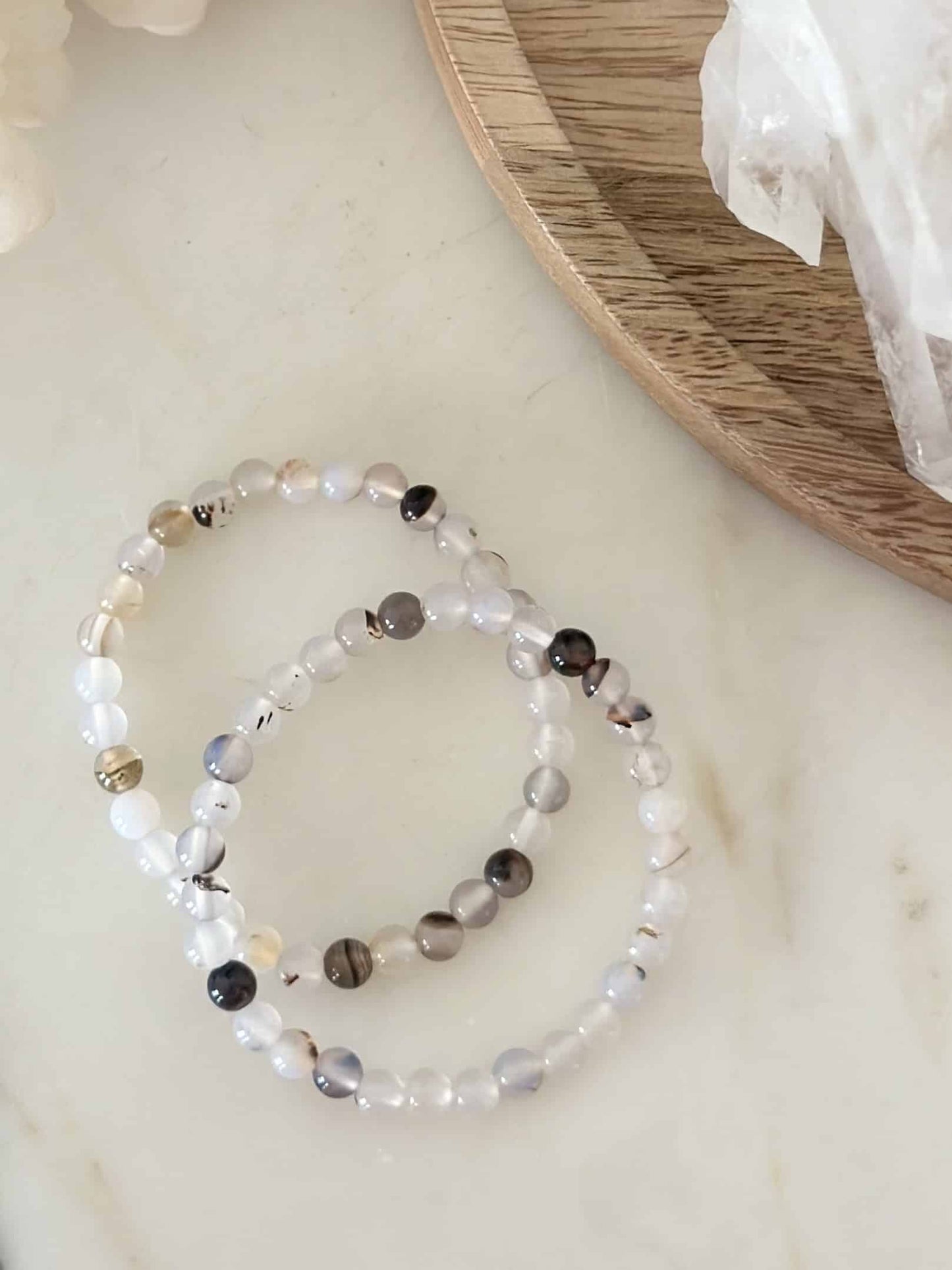 To armbånd lavet af agat natursten på et lyst bord ved en træplade.