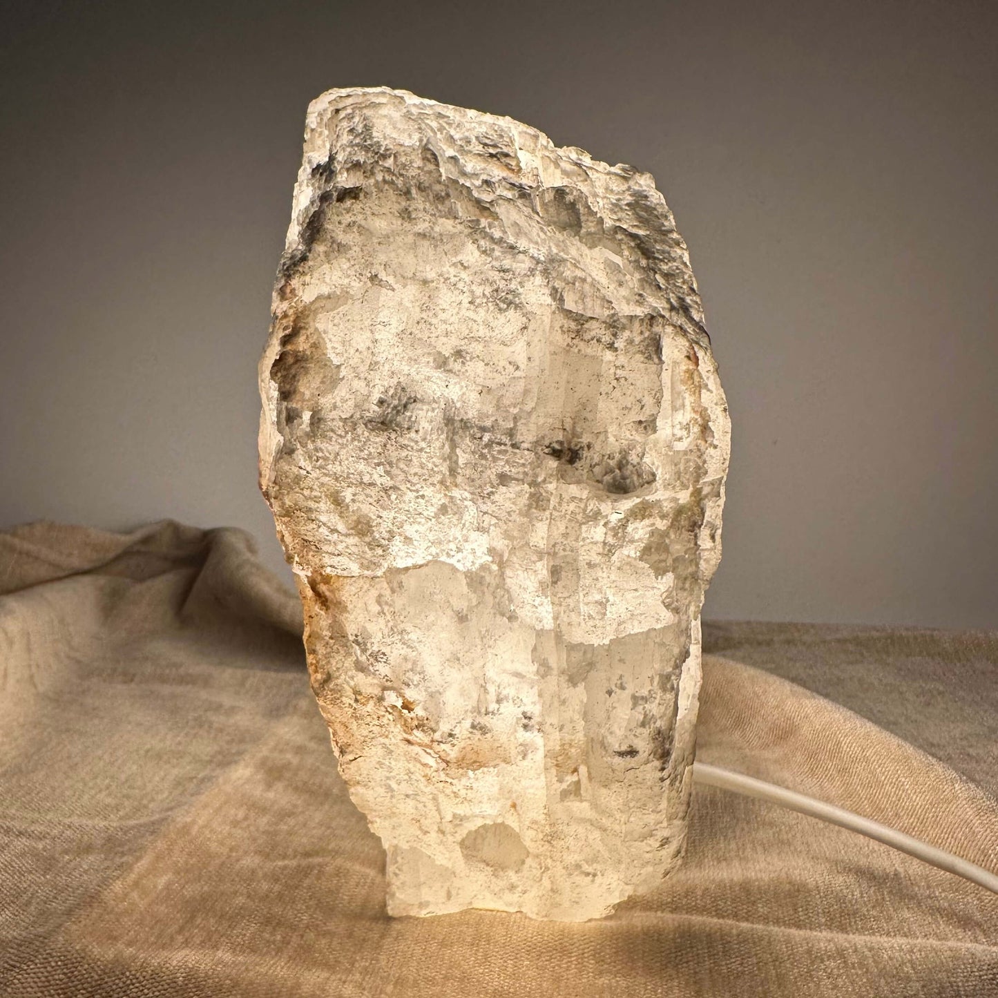 Mexicansk Selenit lampe på en lys klud, der udsender et varmt og blødt lys i et dæmpet rum.