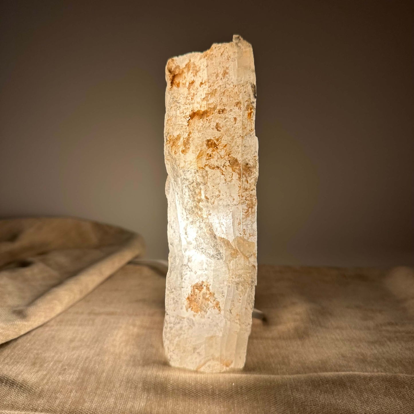 Mexicansk Selenit lampe nr 26 oplyst, står på et blødt underlag mod en mørk baggrund.