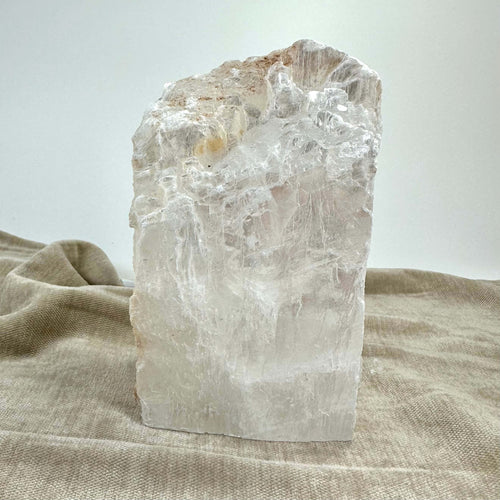 Mexicansk Selenit lampe nr 46 med rå, krystallinsk struktur på en lys brun stofbaggrund.