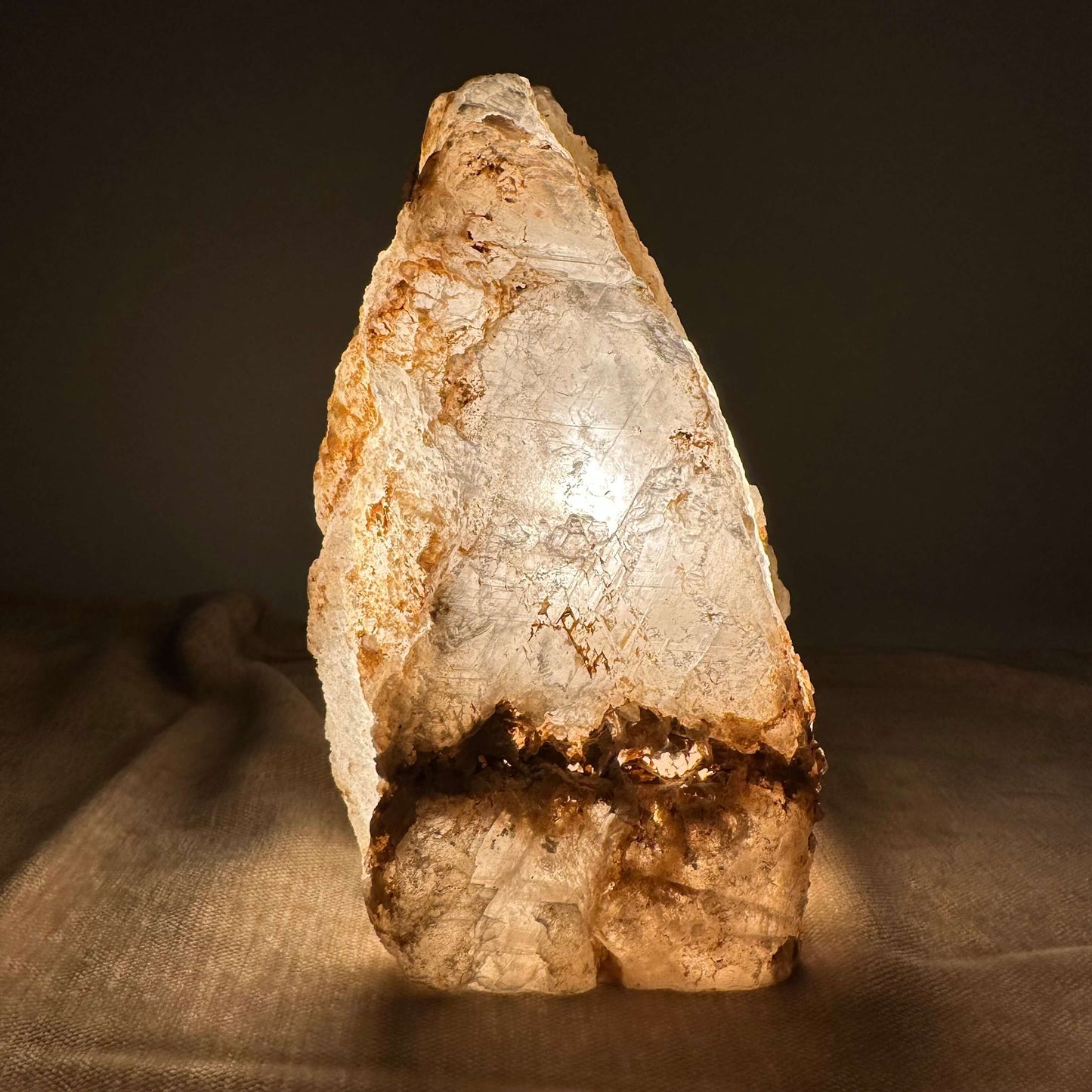 Mexicansk Selenit lampe nr 44 gløder varmt i et mørkt rum, og fremhæver de naturlige strukturer i krystallen.