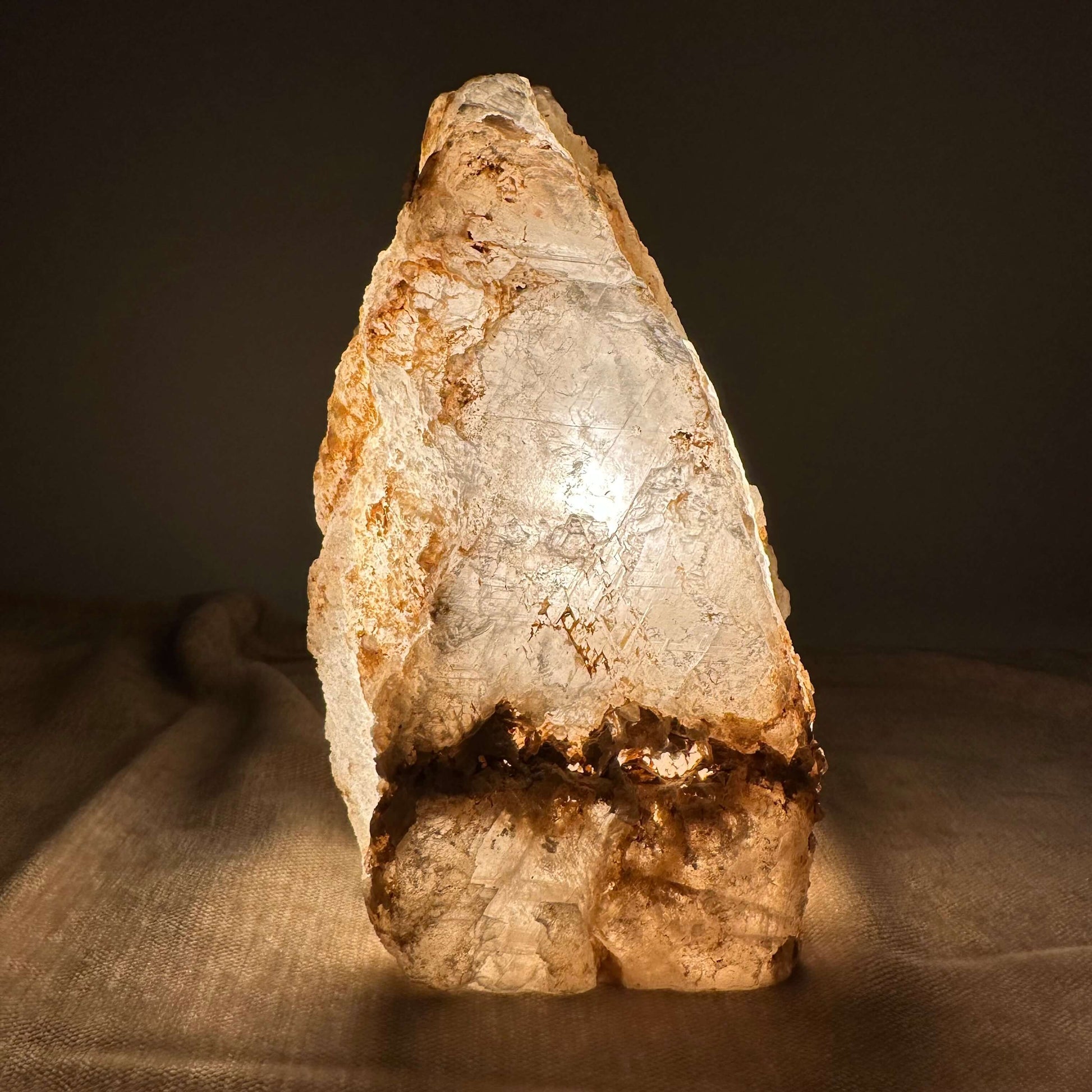 Mexicansk Selenit lampe nr 44 gløder varmt i et mørkt rum, og fremhæver de naturlige strukturer i krystallen.