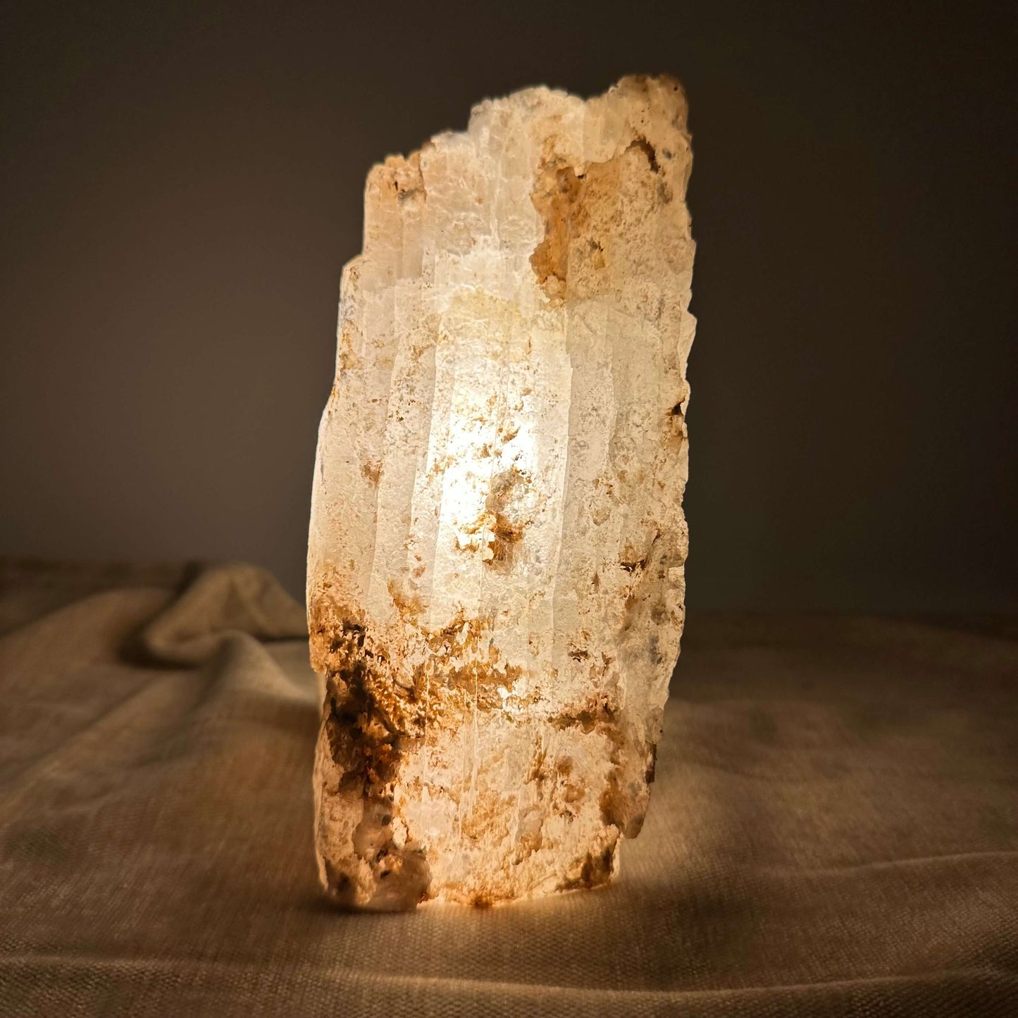 Mexicansk Selenit lampe nr 44 lyser blødt op på en beige baggrund, der fremhæver dens naturlige tekstur og nuance.