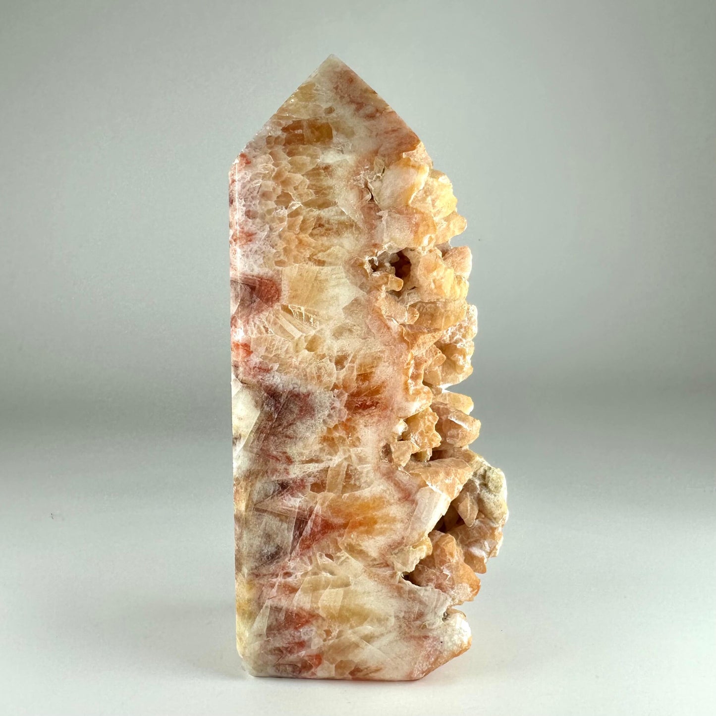 Calcit hundetand med varm farve gradient og krystalliseret tekstur på hvid baggrund.