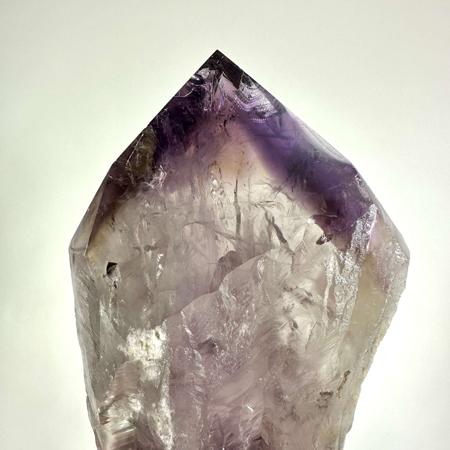 Ametyst scepter med krystalstruktur og lys lilla farve, mod hvid baggrund.