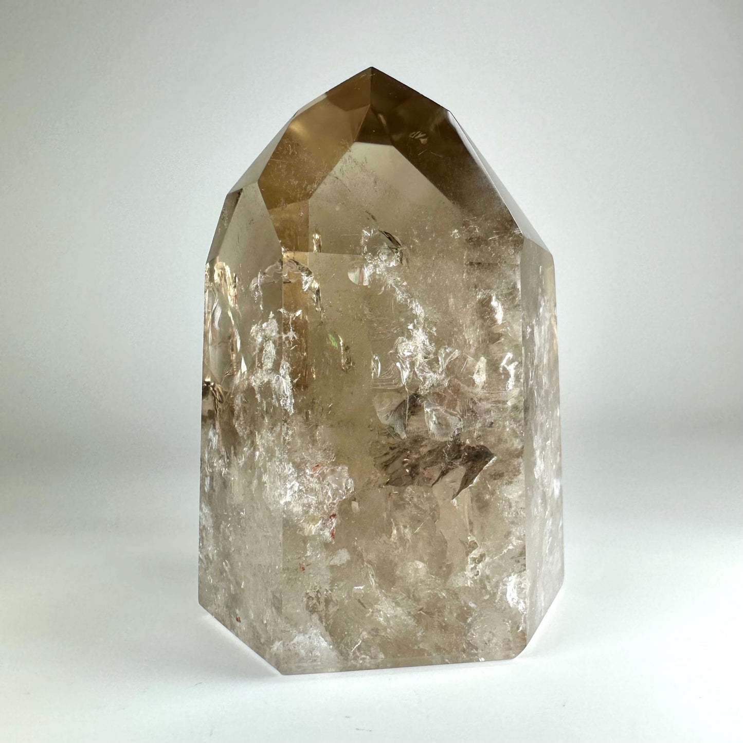 Citrin tårn med gennemsigtigt lys brunt krystal, der reflekterer lyset på hvid baggrund.