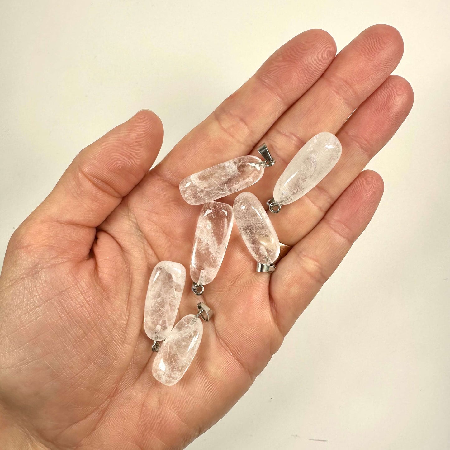 Hånd med seks Bjergkrystal vedhæng på en hvid baggrund.