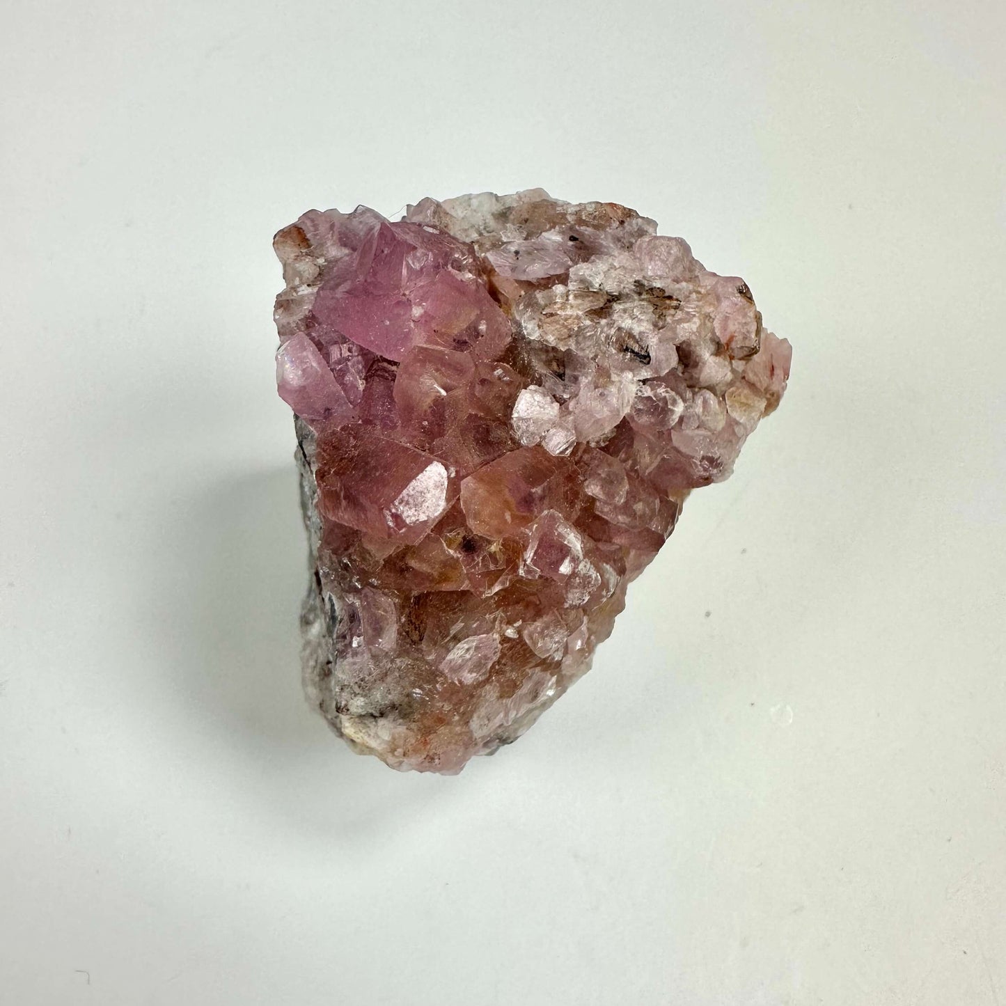 Cobalto calcit klynge med lyserøde krystaller på en lys baggrund.