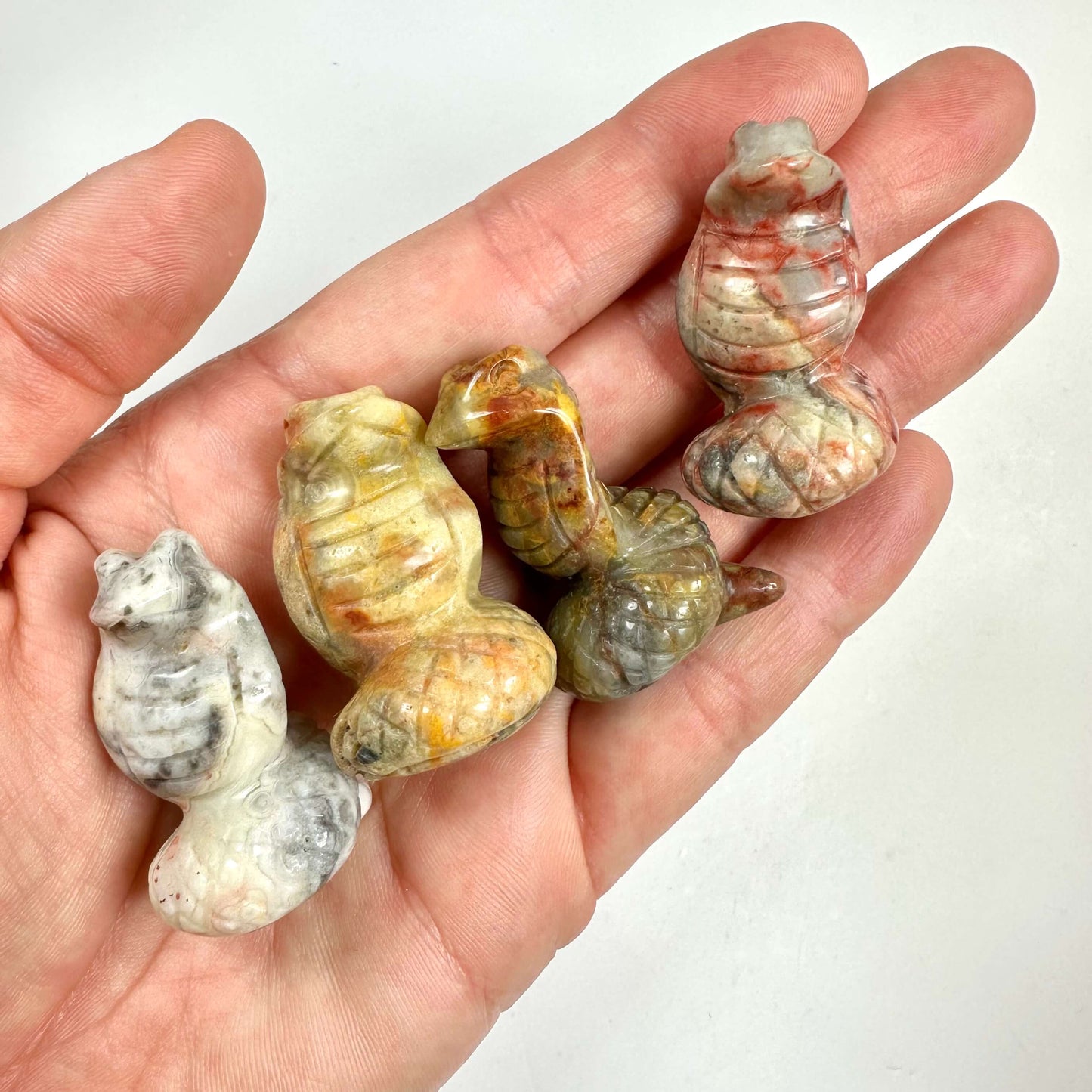 Hånd holder fire Agat crazy lace slangefigurer i forskellige nuancer.
