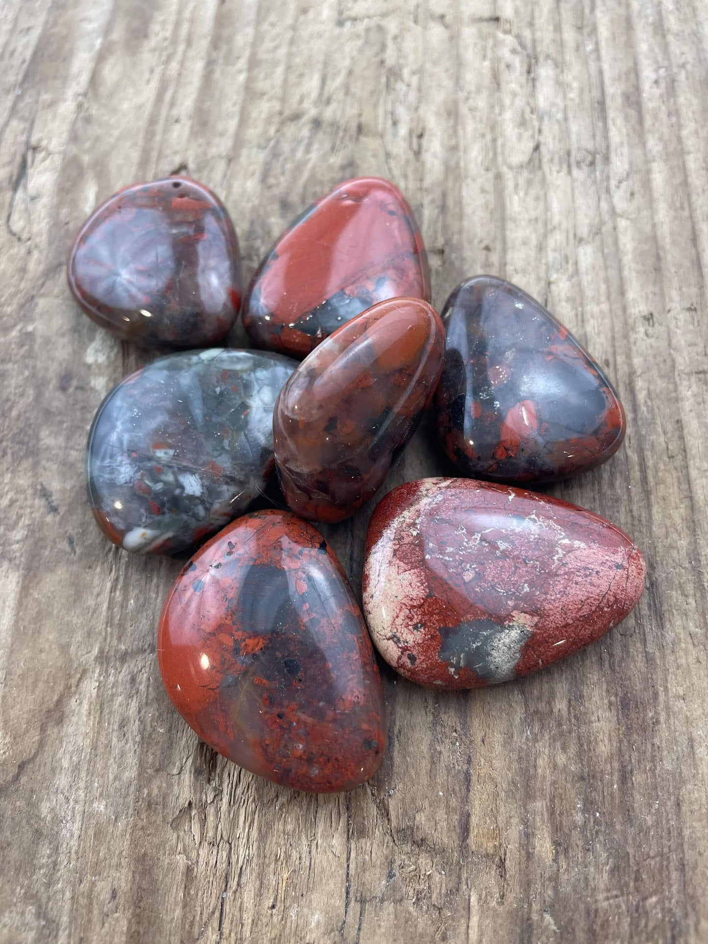 Glansende Jaspis breccie flad sten på træbaggrund.