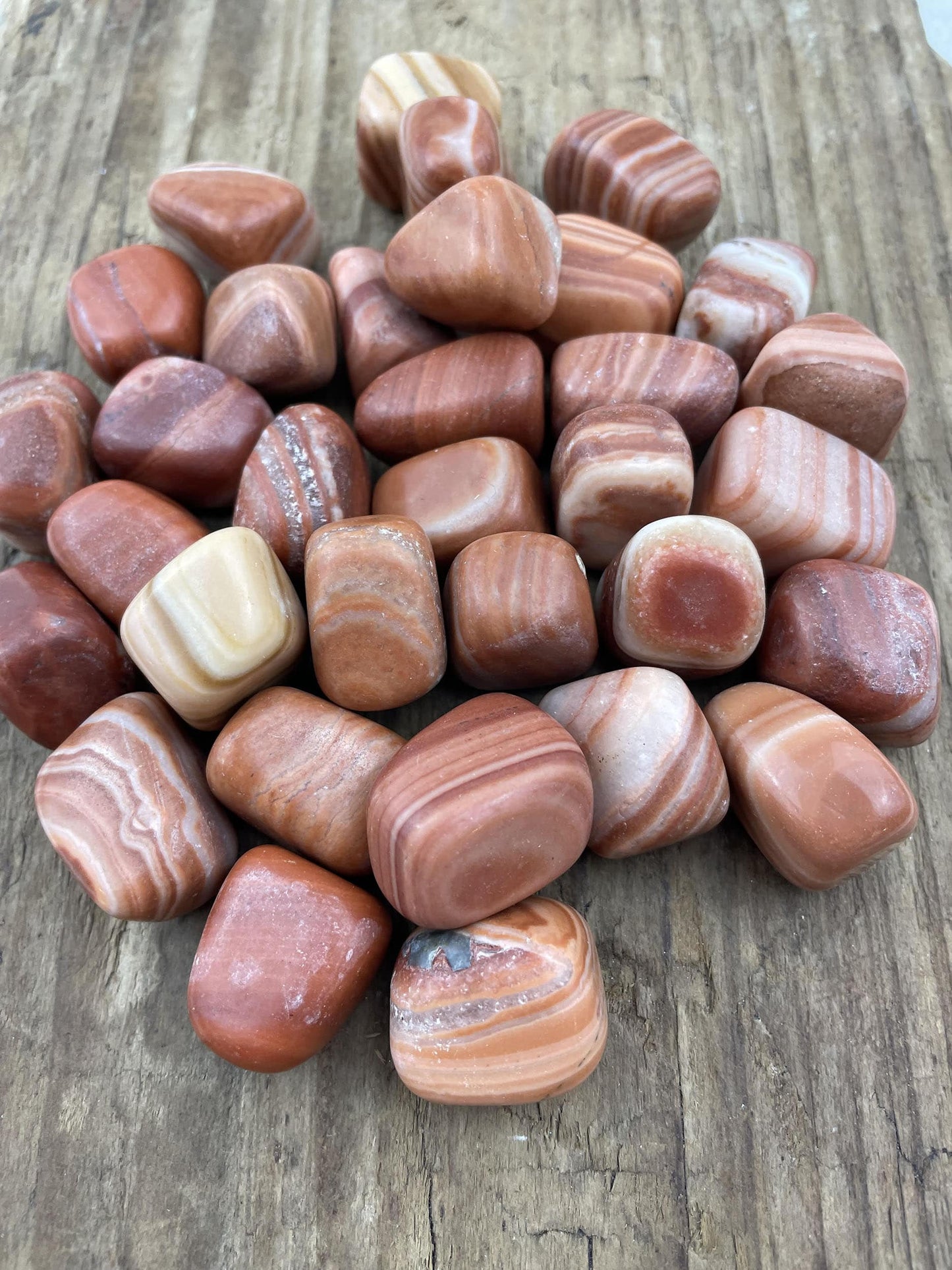 Røde og hvide Mudlane lommesten på en træoverflade.