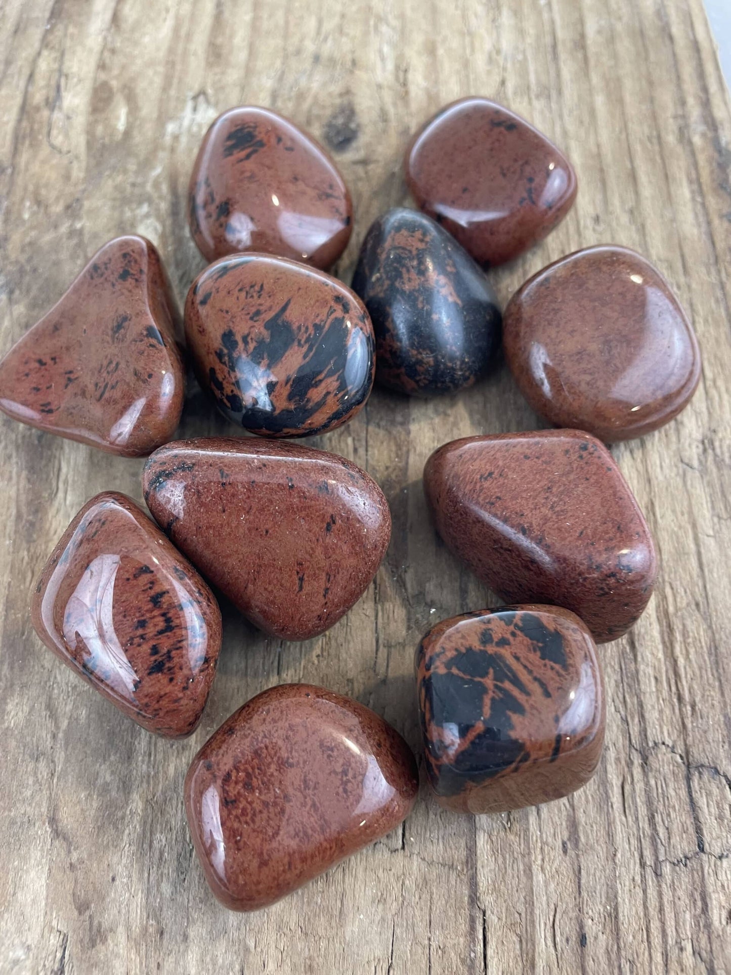 Polerede mahogni obsidiansten på en rustik træoverflade.