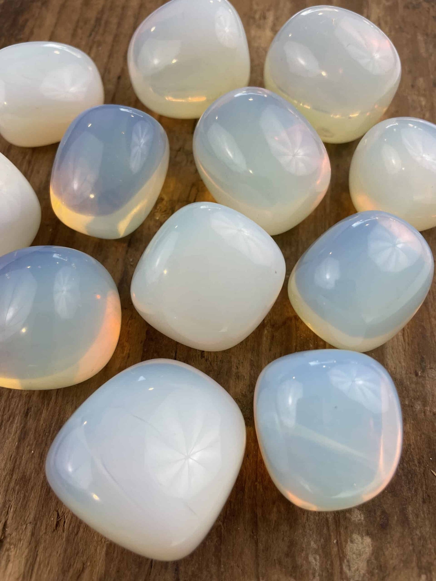 Glansfulde opalitsten ligger på en træoverflade, viser deres iriserende nuancer i lyset.