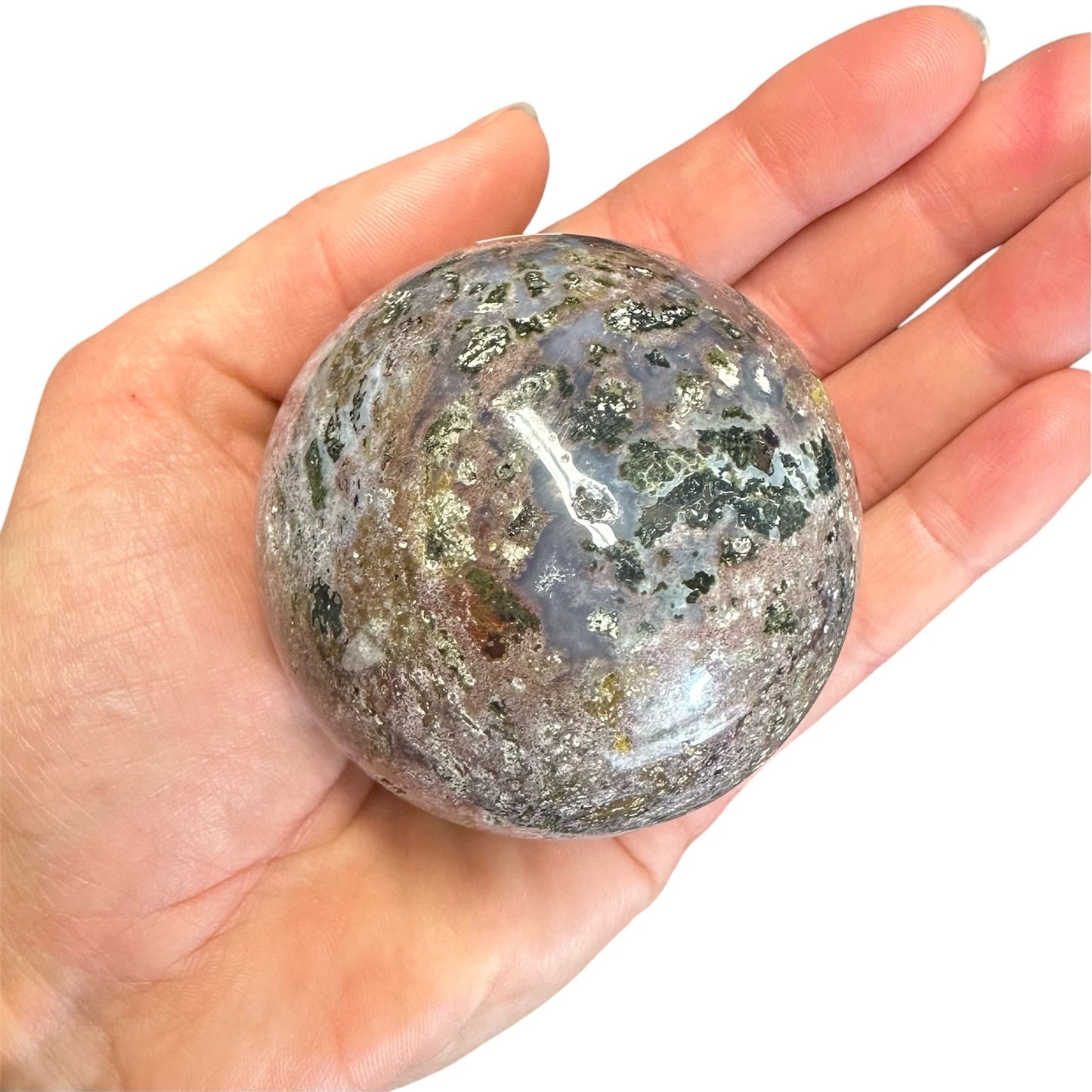 En Jaspis hav kugle holdt i en hånd, med et varieret marmoreret mønster i naturlige farver.