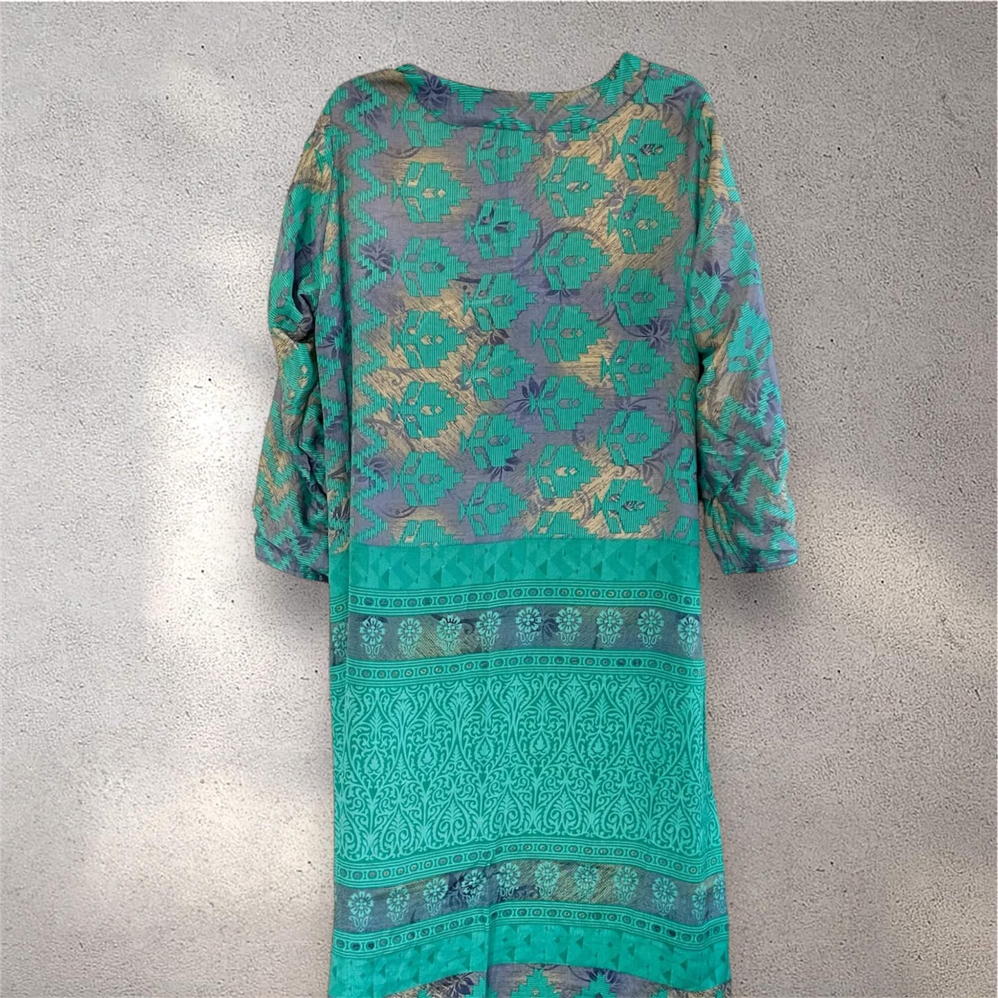 Grøn og lilla kimono med detaljeret mønster på grå baggrund.