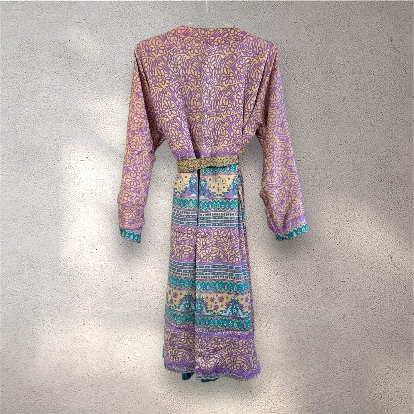 Lilla og gul mønstret kimono hængt på en hvid væg.