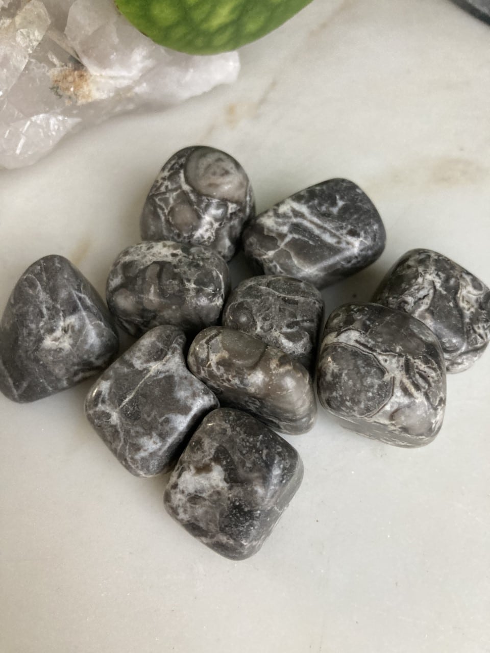 Gruppe af polerede bambussten med grå og hvide mønstre ligger på en lys overflade.