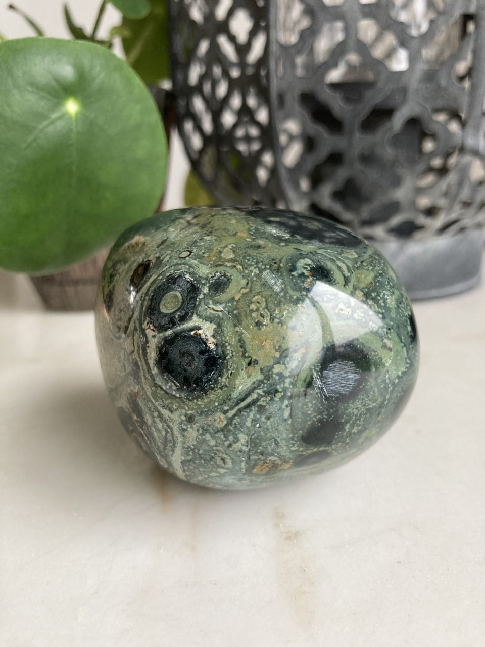 Stor Jaspis Kabamba sten med grønne og sorte mønstre foran dekorativ baggrund.