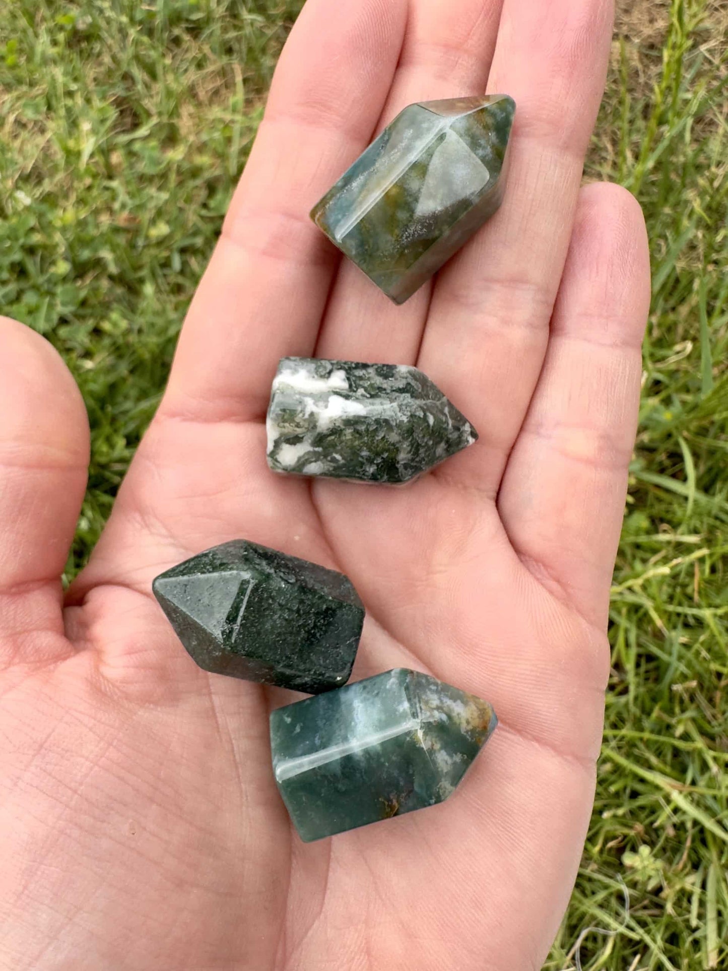 Fire Mos Agat mini tårne ligger i en håndflade, omgivet af græs.