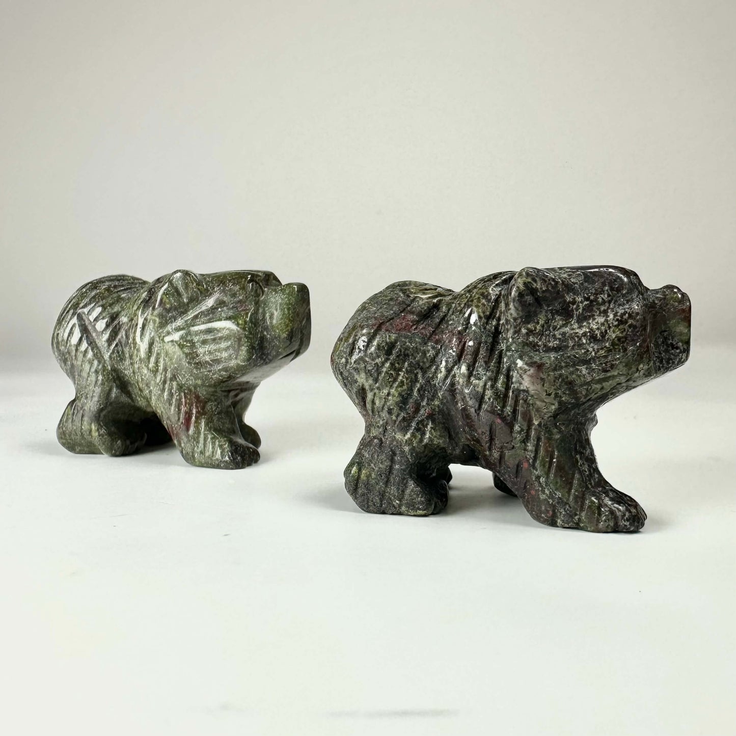 To statuer af bjørne skåret i Drageblod, placeret på en hvid baggrund.