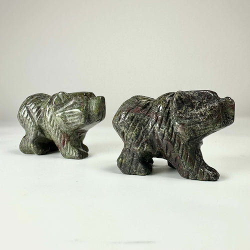 To statuer af bjørne skåret i Drageblod, placeret på en hvid baggrund.