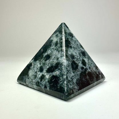Grøn og sort pyramide lavet af natursten på en hvid baggrund.