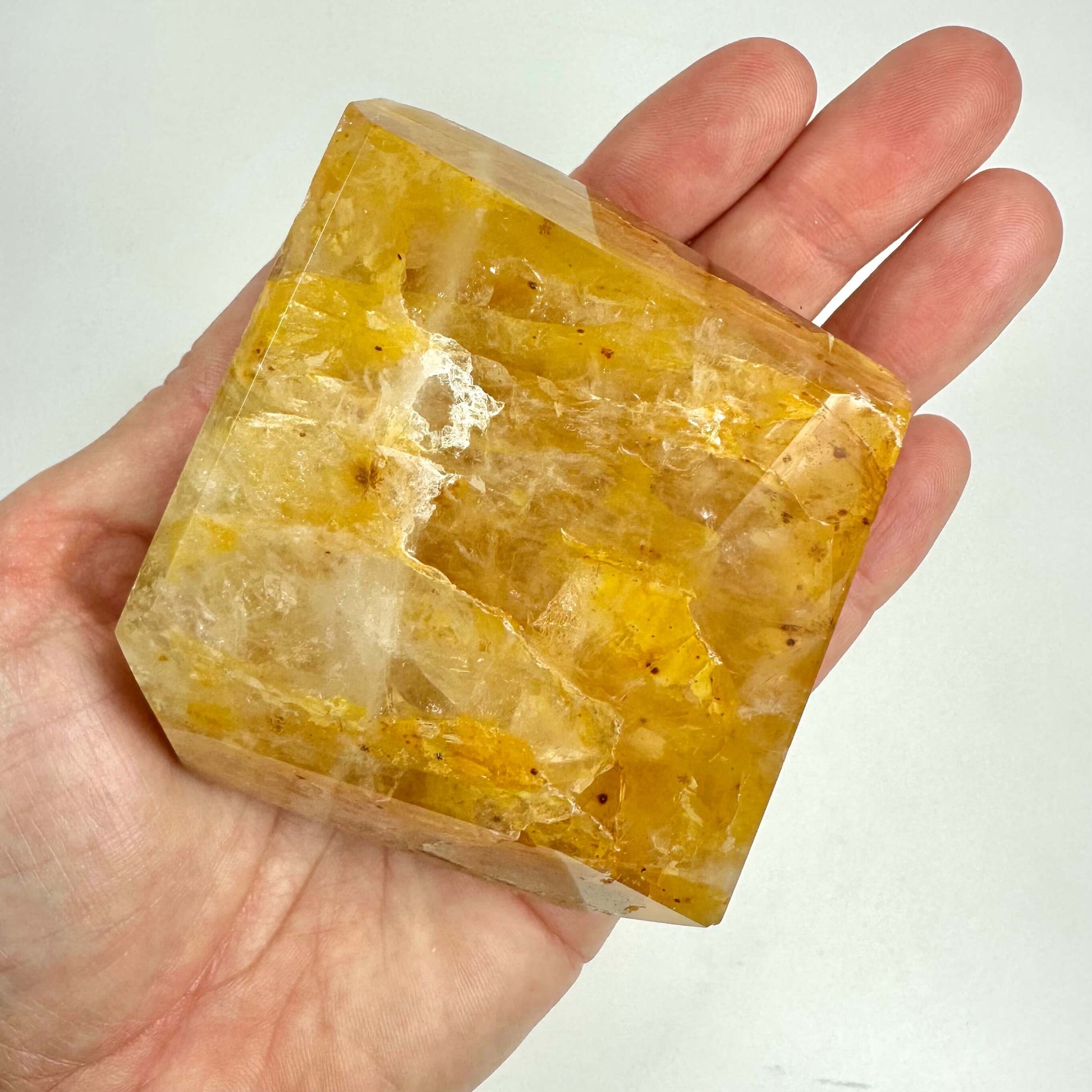 Hånd holder en Golden Healer krystal i fri form, gylden og gennemsigtig med naturlige mønstre.