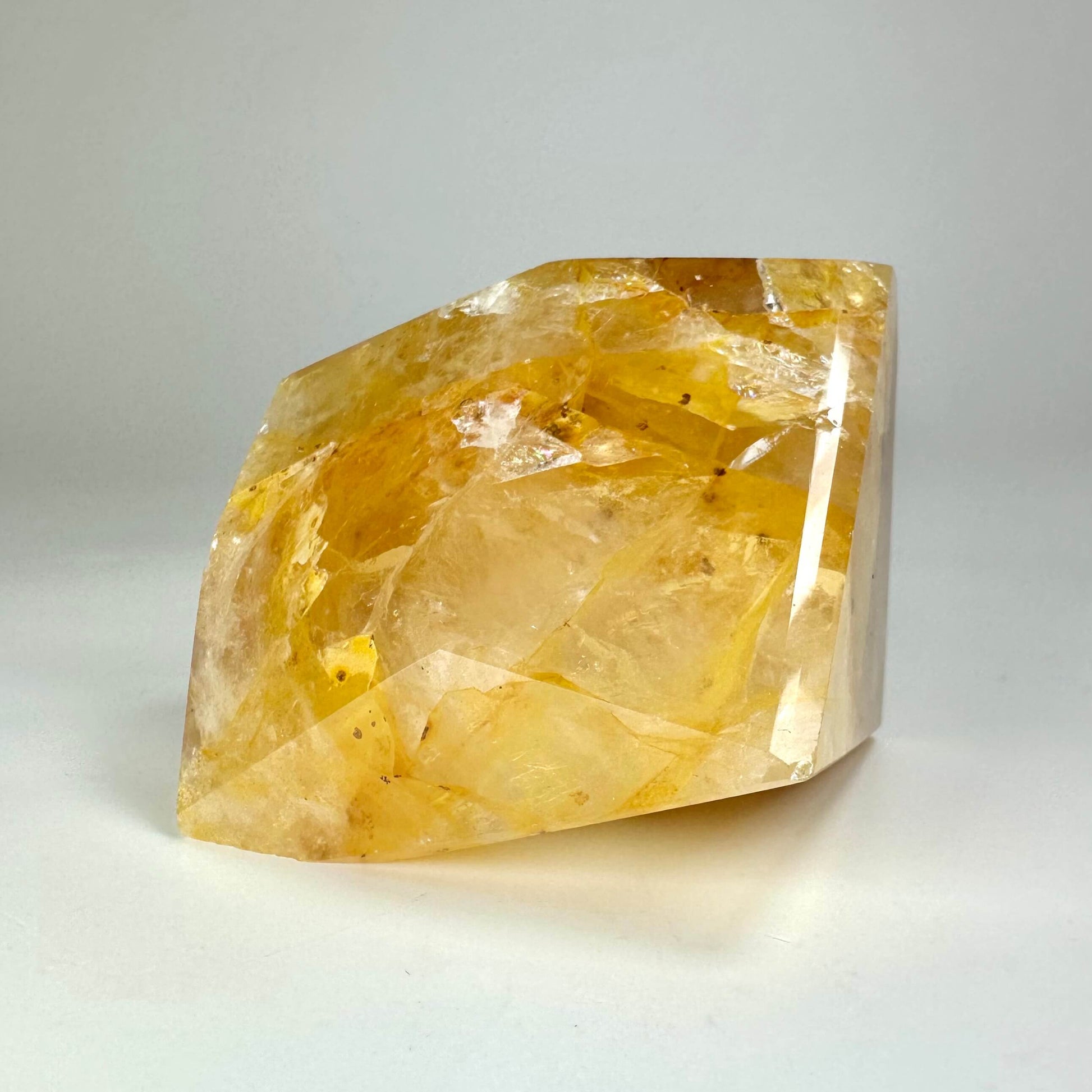 En stor, gul Golden Healer krystal med en glat overflade på en hvid baggrund.