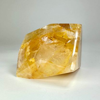En stor, gul Golden Healer krystal med en glat overflade på en hvid baggrund.