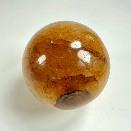 Golden healer kugle med gylden farve og naturlige mønstre på en lys baggrund.