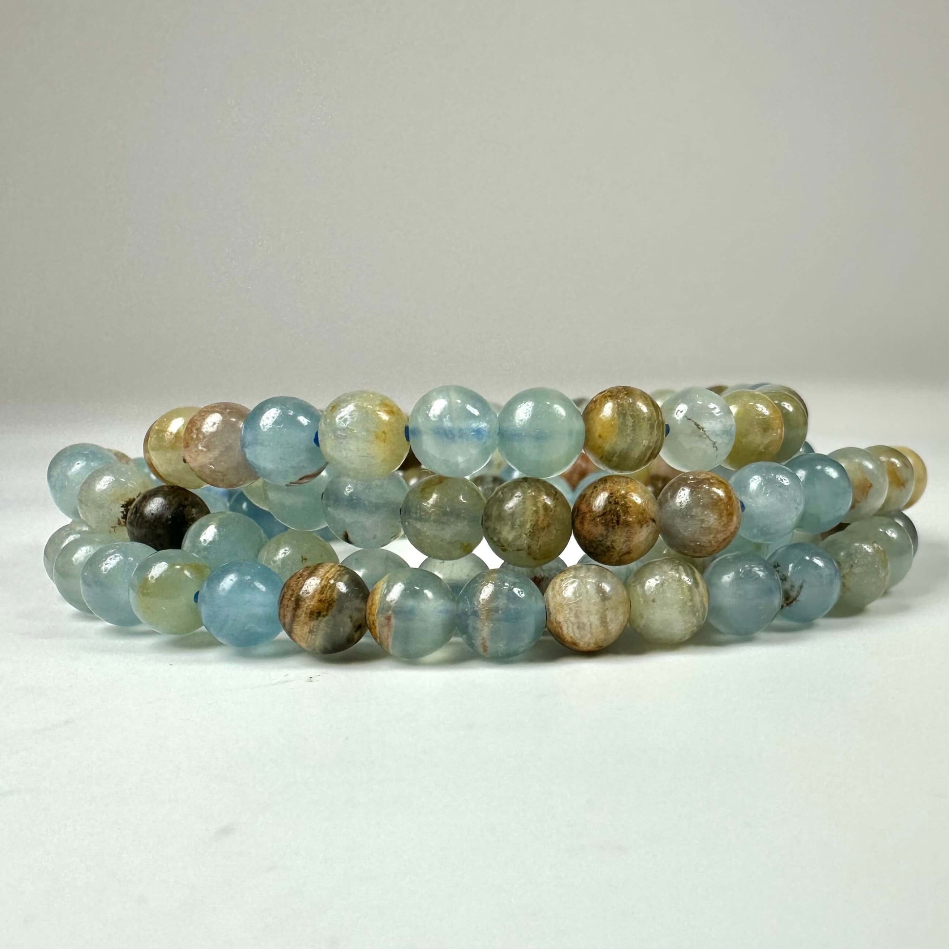 Armbånd med blå og beige sten: Akvatin lemurie calcit armbånd 6mm i flere lag.