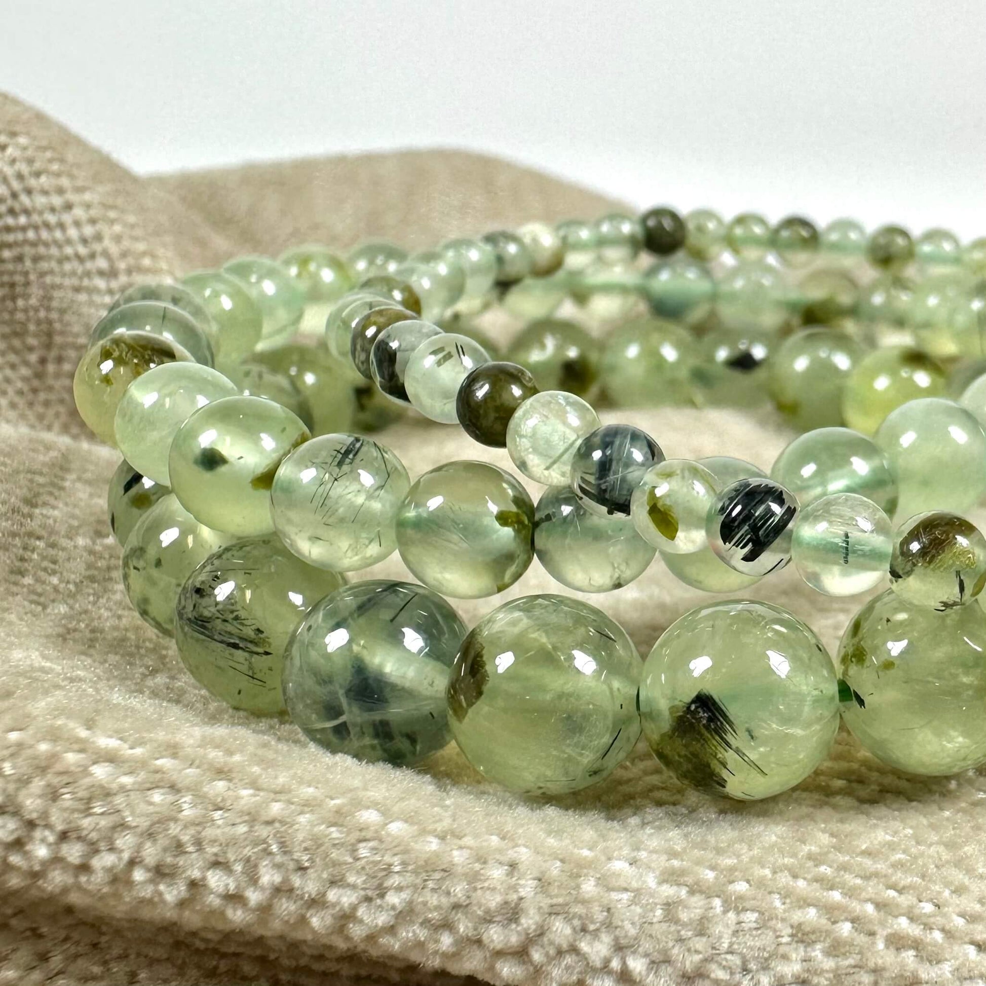 Grønne perlekæder på tekstil, med nuancer af grøn og gennemsigtig overflade.