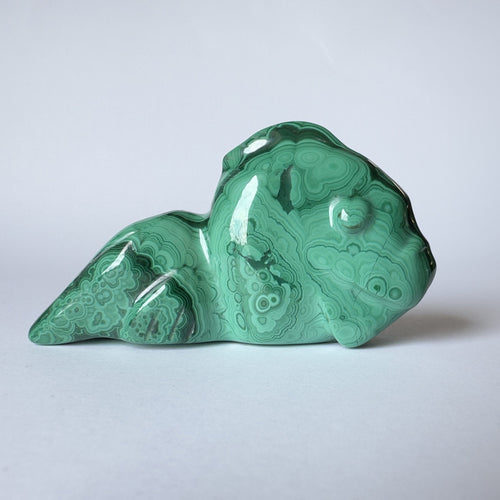 Grøn malakit skulptur formet som en slørhale på hvid baggrund.