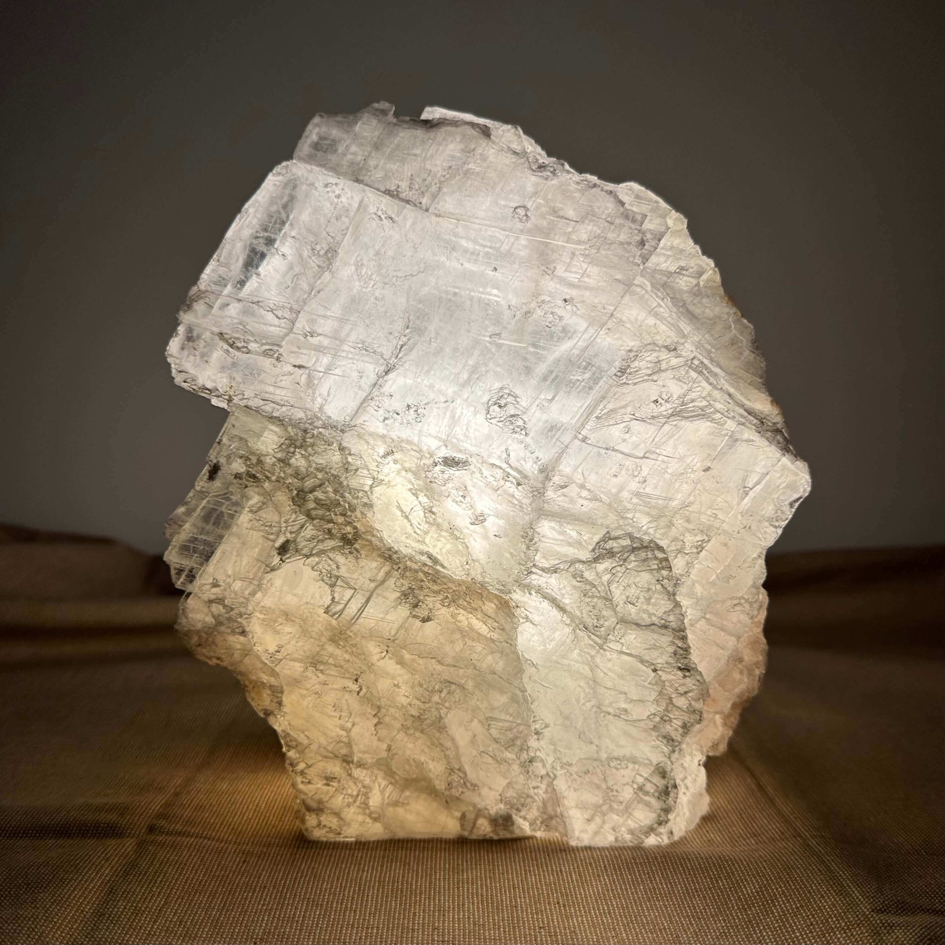 Krystalstruktur af gennemsigtigt, lysende mineral på en brun overflade.